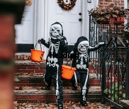 Two skeleton trick-or-treaters descend a staircase