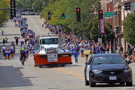 A police car and public works vehicle drive in the parade