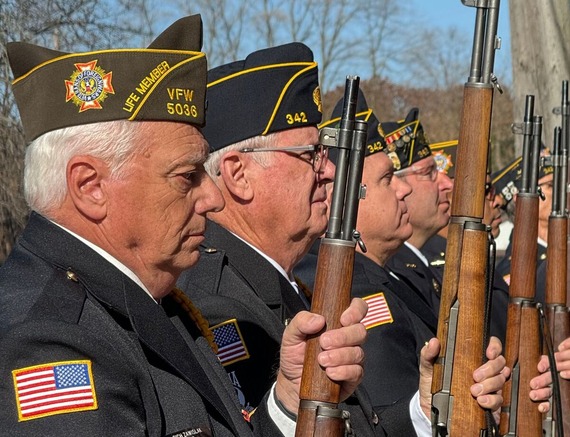 veterans with guns perform a salute.