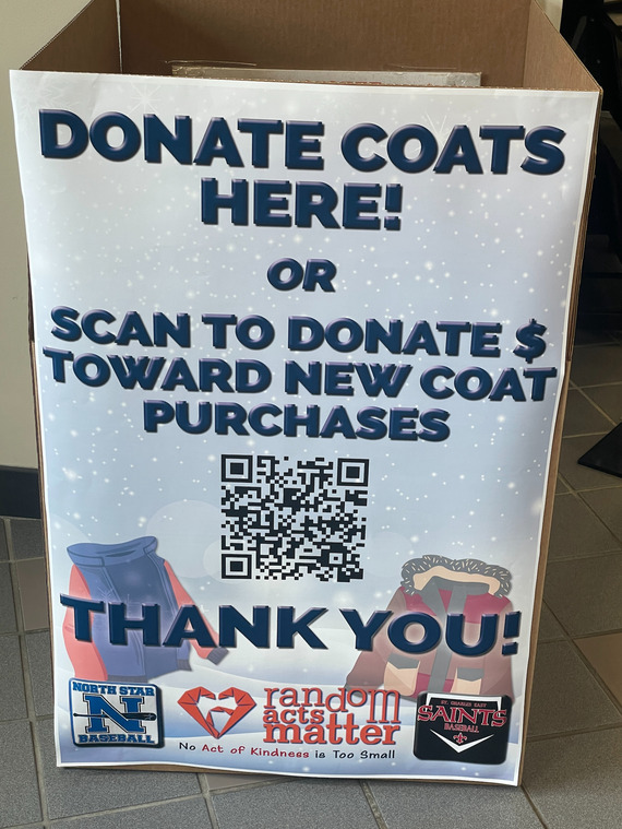A donation box with a sign and QR code for a coat drive in the lobby.
