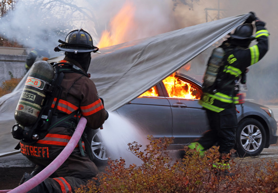 A firefighter puts our a car fire.