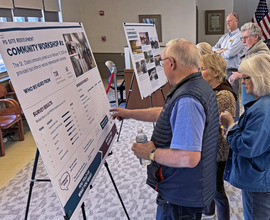 Several adults look at a poster board with ideas for the site.