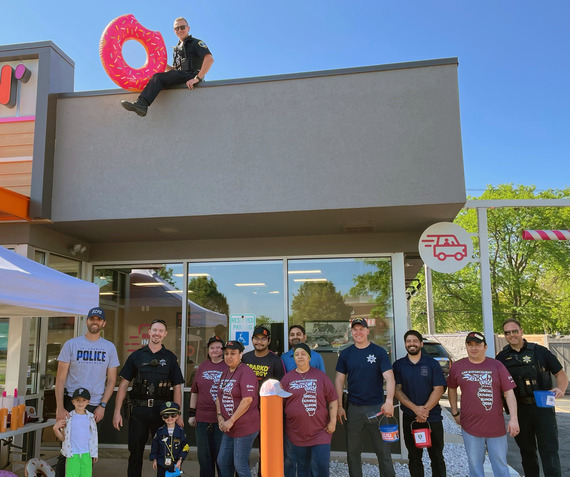 Cops, Dunkin' employees and Special Olympics athletes post in front of a Dunkin' location in St. Charles.