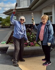 Two members of the Pottawatomie Garden Club pose with shovels in their hands during a spring planting.