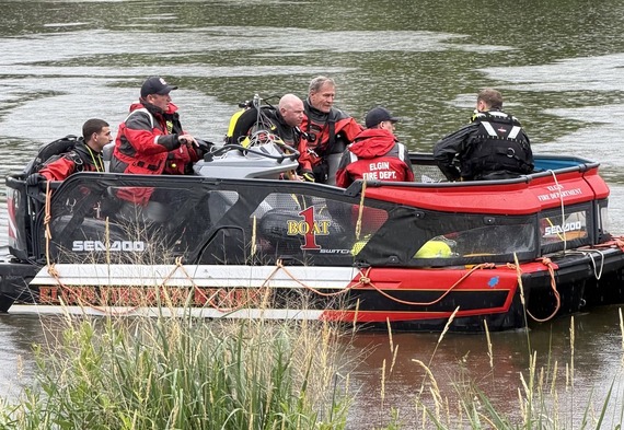 Divers on a boat on a body of water perform a search.