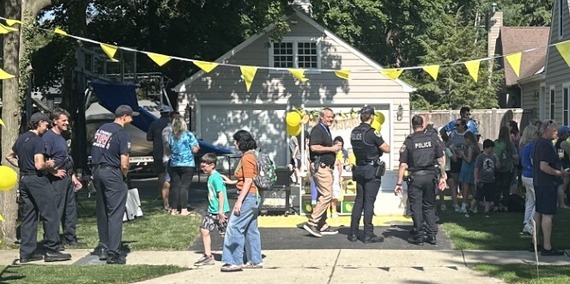 Firefighters and police officers enjoy lemonade from a neighborhood stand.