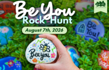 A hand holding a painted rock over a lot of other painted rocks.