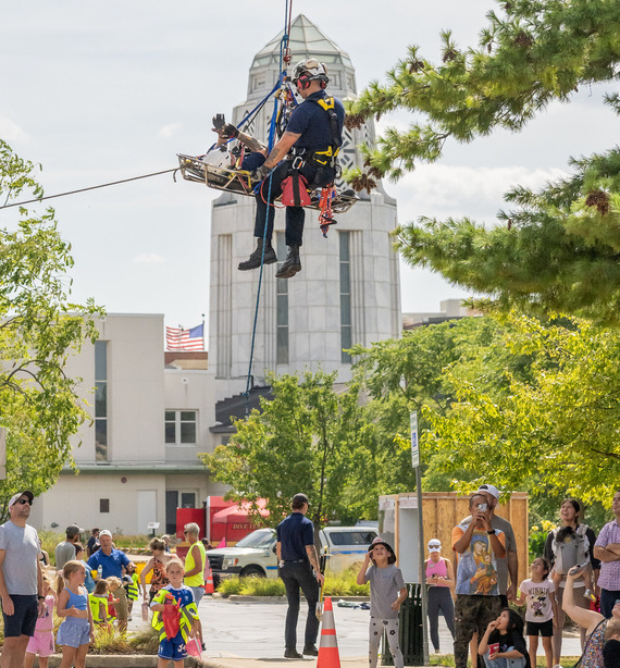 A firefighter performs a rescue demo from a rooftop.