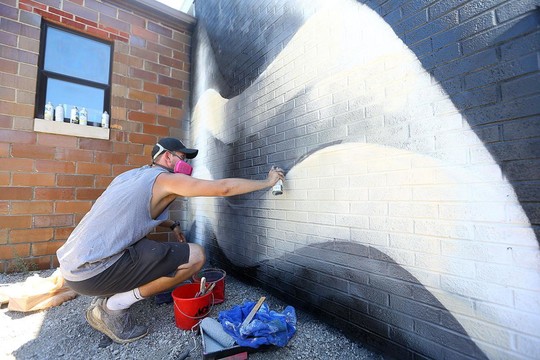 Artist spray painting mural outside