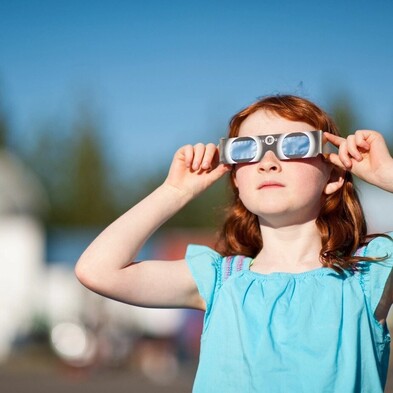 Young girl wearing solar eclipse glasses