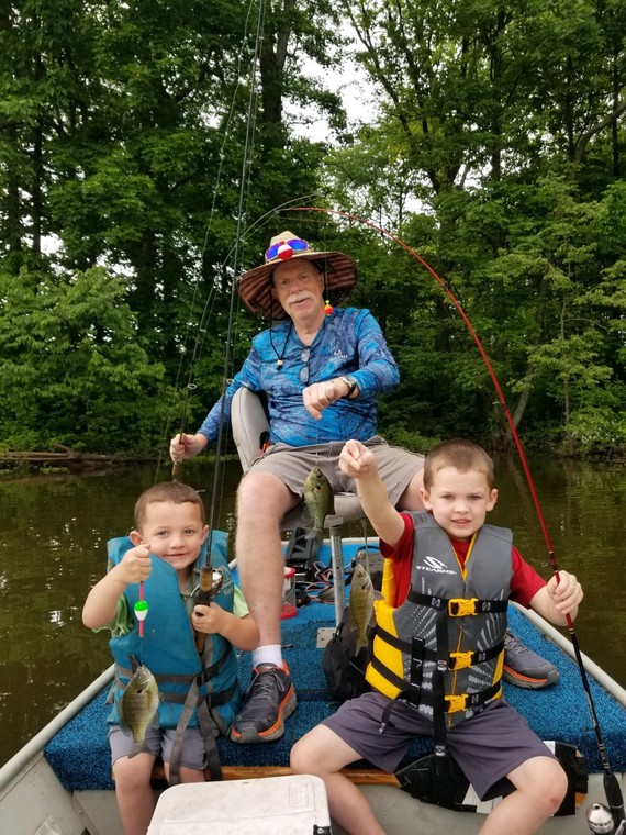 A man and two children fishing on a boat. 
