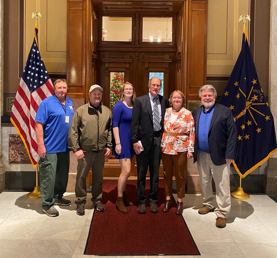 A group of DNR employees posing for a photo in front of flags.