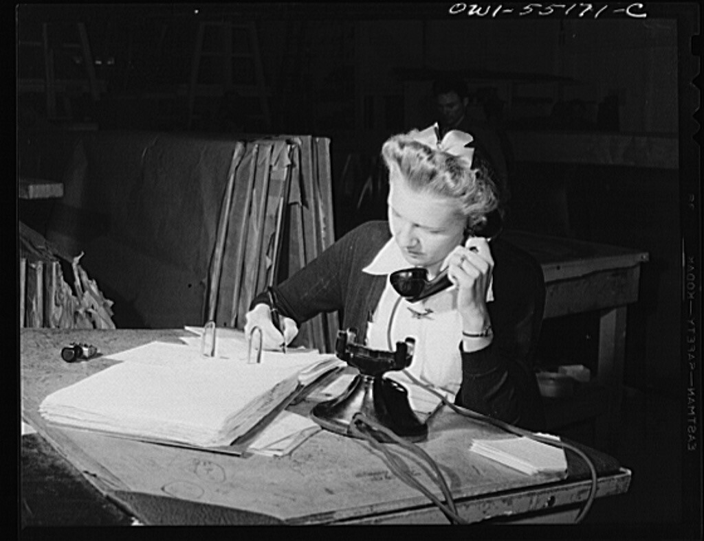 Vintage black-and-white photo of a woman on a phone call.