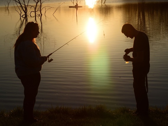 Two people fishing at sunset.