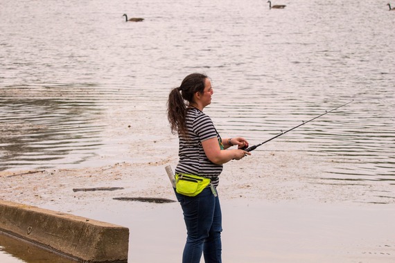 A woman shoreline fishing.