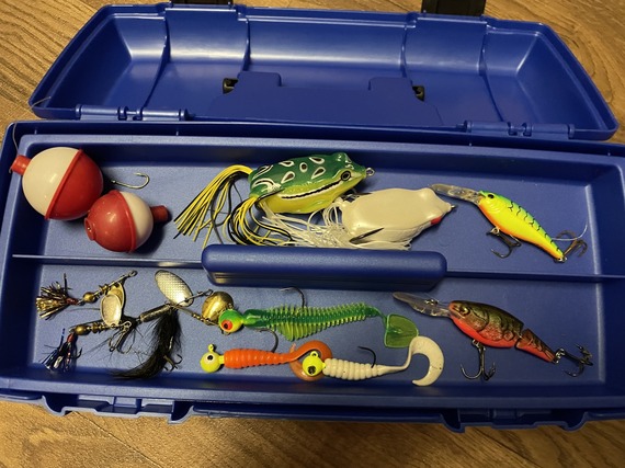 A packed tackle box on floorboards.