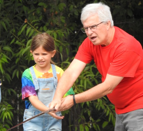 A man helping a young girl fish.