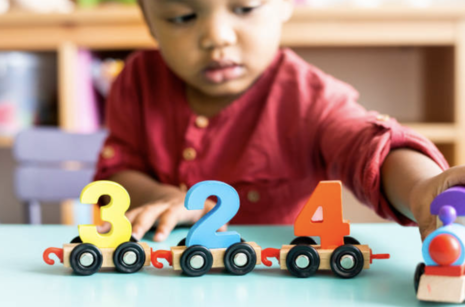 Child playing with toy train with number blocks.