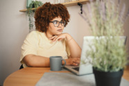 Woman sitting at a table looking at a laptop