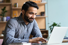 Man sitting at desk looking at laptop