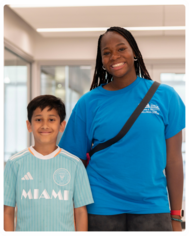 A young boy standing (left) standing next to a program leader (right)