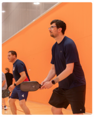 A man in a "ready" stance with a pickleball paddle