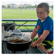 A young boy helping make a dessert in a Dutch oven