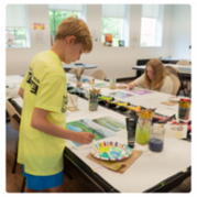 A boy painting on a canvas during an art camp