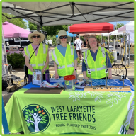 A group of three west lafayette tree friend volunteers standing together at a Tree Friends booth at the WLFM