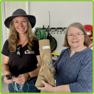 Two Tree Friend volunteers preparing and holding up a sapling grab bag for Arbor Day Celebration