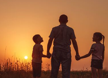 Image of father and children walking towrd sunset