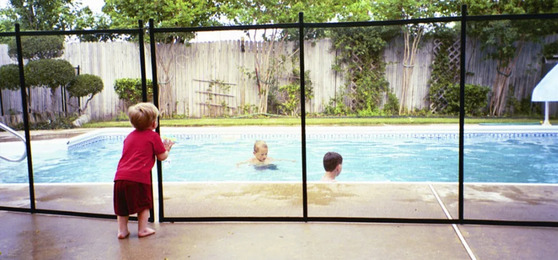 Image of a child standing behind a pool fence