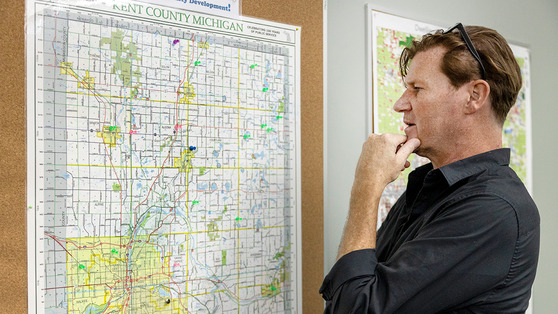 Image of a man looking at a Kent County map on the wall, with pins in it