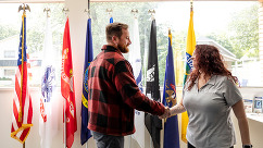 Image of two people shaking hands in front of a bunch of flags