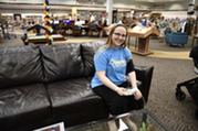 Picture of Kent District Library Branch Shows Staff Member Sitting on a Sofa and Using a Blood Pressure Monitor
