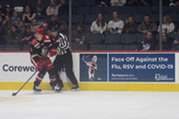 Grand Rapids Griffins hockey player and ref positioned in front of a billboard promoting flu shots