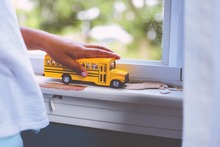 Image of a kid playing a toy bus on a window sill