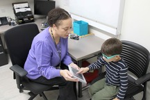 Image of a Health Department worker doing a vision test with a child