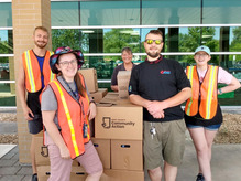 Image of a team in safety vests smiling, at a food distribution event