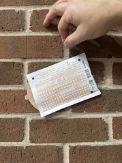 Picture of a Hand Holding a Radon Test Kit Against a Brick Wall