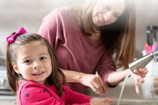 Image of mother helping a girl at the sink, with running water