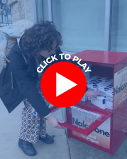A Woman Gets Naloxone from a Distribution Site with a Play Button Icon that Reads Click to Play