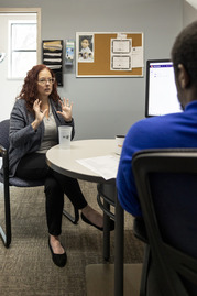 Image of a woman talking to a man behind a desk