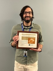 People's Champion Award Winner Josh Potter Smiles as he Poses with the Certificate