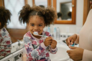 Young Girl Smiling as she Brushes her Teeth at the Bathroom Sink