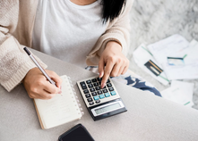 Image of a woman budgeting finances with a calculator and pen