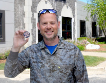 Man holding up 250 challenge coin