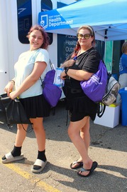 Two Girls Pose with Items from the Kent County Health Department While Attending a Community Event