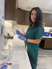 Photo of a Female Public Health Nurse in Green Scrubs Preparing a Vaccine for an Appointment