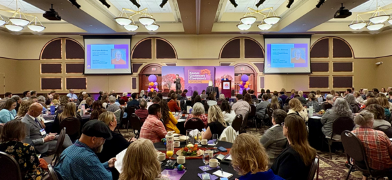 Kansas Governor's Conference on Aging header image of Sec. Howard speaking to crowd in large conference room